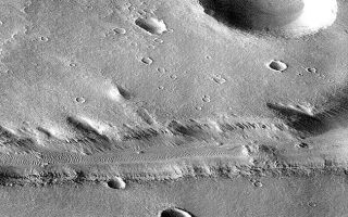 <h1>PIA00943:  Subsection of Nirgal Vallis Image</h1><div class="PIA00943" lang="en" style="width:630px;text-align:left;margin:auto;background-color:#000;padding:10px;max-height:150px;overflow:auto;">This image is a subsection of the MGS Nirgal Vallis "B" image (PIA00942).<p>This subsection of frame P006_05 is shown here at reduced resolution because the full image is almost 7 MBytes in size. Because the MOC acquires its images one line at a time, the cant angle towards the sun-lit portion of the planet, the spacecraft orbital velocity, and the spacecraft rotational velocity combined to significantly distort the image. However, even in this reduced resolution version, dunes can be seen in the canyon and in areas on the upland surface around the canyon.<p>Nirgal Vallis is one of a number of canyons called valley networks or runoff channels. Much of the debate concerning the origin of these valleys centers on whether they were formed by water flowing across the surface, or by collapse and upslope erosion associated with groundwater processes. At the resolution of this image, it is just barely possible to discern an interwoven pattern of lines on the highland surrounding the valley, but it is not possible to tell whether this is a pattern of surficial debris (sand or dust), as might be expected with the amount of crater burial seen, or a pattern of drainage channels. With 4X better resolution from its mapping orbit, MOC should easily be able to tell the difference between these two possibilities.<p>Launched on November 7, 1996, Mars Global Surveyor entered Mars orbit on Thursday, September 11, 1997. The spacecraft has been using atmospheric drag to reduce the size of its orbit for the past three weeks, and will achieve a circular orbit only 400 km (248 mi) above the surface early next year. Mapping operations begin in March 1998. At that time, MOC narrow angle images will be 5-10 times higher resolution than these pictures.<p>Malin Space Science Systems and the California Institute of Technology built the MOC using spare hardware from the Mars Observer mission. MSSS operates the camera from its facilities in San Diego, CA. The Jet Propulsion Laboratory's Mars Surveyor Operations Project operates the Mars Global Surveyor spacecraft with its industrial partner, Lockheed Martin Astronautics, from facilities in Pasadena, CA and Denver, CO.<br /><br /><a href="http://photojournal.jpl.nasa.gov/catalog/PIA00943" onclick="window.open(this.href); return false;" title="Voir l'image 	 PIA00943:  Subsection of Nirgal Vallis Image	  sur le site de la NASA">Voir l'image 	 PIA00943:  Subsection of Nirgal Vallis Image	  sur le site de la NASA.</a></div>
