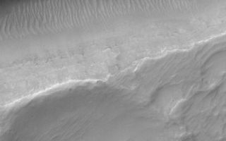 <h1>PIA01046:  Sirenum Fossae Trough</h1><div class="PIA01046" lang="en" style="width:600px;text-align:left;margin:auto;background-color:#000;padding:10px;max-height:150px;overflow:auto;"><a href="/figures/moc2_248b.gif"></a><p>The Mars Global Surveyor (MGS) Mars Orbiter Camera (MOC) orbits the red planet twelve times each day. The number of pictures that MOC can take varies from orbit to orbit, depending upon whether the data are being stored in MGS's onboard tape recorder for playback at a later time, or whether the data are being sent directly back to Earth via a real-time radio link. More data can be acquired during orbits with real-time downlink.<p>During real-time orbits, the MOC team often will take a few random or semi-random pictures in between the carefully-selected, hand-targeted images. On rare occasions, one of these random pictures will surprise the MOC team. The picture shown here is an excellent example, because the high resolution view (top) is centered so nicely on a trough and an adjacent, shallow crater that it is as if someone very carefully selected the target for MOC. The high-resolution view covers an area only 1.1 km (0.7 mi) wide by 2.3 km (1.4 mi) long. Hitting a target such as this with such a small image is very difficult to do, on purpose, because there are small uncertainties in the predicted orbit, the maps used to select targets, and the minor adjustments of spacecraft pointing at any given moment. Nevertheless, a very impressive image was received.<p>The high resolution view crosses one of the troughs of the Sirenum Fossae near 31.2°S, 152.3°W. The context image (above) was acquired at the same time as the high resolution view on July 23, 2000. The small white box shows the location of the high resolution picture. The lines running diagonally across the context image from upper right toward lower left are the Sirenum Fossae troughs, formed by faults that are radial to the volcanic region of Tharsis. Both pictures are illuminated from the upper left. The scene shows part of the martian southern hemisphere nearly autumn.<br /><br /><a href="http://photojournal.jpl.nasa.gov/catalog/PIA01046" onclick="window.open(this.href); return false;" title="Voir l'image 	 PIA01046:  Sirenum Fossae Trough	  sur le site de la NASA">Voir l'image 	 PIA01046:  Sirenum Fossae Trough	  sur le site de la NASA.</a></div>