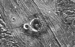 <h1>PIA01088:  Nergal Crater on Ganymede</h1><div class="PIA01088" lang="en" style="width:648px;text-align:left;margin:auto;background-color:#000;padding:10px;max-height:150px;overflow:auto;">Two impact craters surrounded by an unusual ejecta blanket dominate this high resolution image of the surface of Jupiter's moon, Ganymede. NASA's Galileo spacecraft imaged this region as it passed Ganymede during its second orbit through the Jovian system. North is to the top of the picture and the sun illuminates the surface from the southeast. Nergal, the larger crater, is about eight kilometers (five miles) in diameter, while the smaller (unnamed) crater to its west is three kilometers (1.8 miles) across. The craters are situated in a region of bright grooved terrain named Byblus Sulcus, located in the northern part of Marius Regio at 39 degrees latitude and 201 degrees longitude. The distinctive ejecta blanket that surrounds them is darker nearer the craters and brighter further away. The inner region of the ejecta is characterized by a lobate appearance indicative of the flow of a liquid (or slushy) substance over the surface. The flow was probably icy surface material melted by the energy released during the impact that formed the crater.<p>The picture covers an area about 48 kilometers (30 miles) by 34 kilometers (21 miles) across at a resolution of 86 meters (287 feet) per picture element. The image was taken on September 6, 1996 by the solid state imaging (CCD) system on NASA's Galileo spacecraft.<p>The Jet Propulsion Laboratory, Pasadena, CA manages the Galileo mission for NASA's Office of Space Science, Washington, DC. JPL is an operating division of California Institute of Technology (Caltech).<p>This image and other images and data received from Galileo are posted on the World Wide Web, on the Galileo mission home page at URL http://galileo.jpl.nasa.gov.<br /><br /><a href="http://photojournal.jpl.nasa.gov/catalog/PIA01088" onclick="window.open(this.href); return false;" title="Voir l'image 	 PIA01088:  Nergal Crater on Ganymede	  sur le site de la NASA">Voir l'image 	 PIA01088:  Nergal Crater on Ganymede	  sur le site de la NASA.</a></div>
