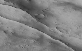 <h1>PIA01158:  Schiaparelli Crater Rim and Interior Deposits - High Resolution Image</h1><div class="PIA01158" lang="en" style="width:457px;text-align:left;margin:auto;background-color:#000;padding:10px;max-height:150px;overflow:auto;">A portion of the rim and interior of the large impact crater Schiaparelli is seen at high resolution in this image acquired October 18, 1997 by the Mars Global Surveyor Orbiter Camera (MOC). The area covered is very small--3.9 X 10.2 km (2.4 X 6.33 mi)--but is seen at 63 times higher resolution than the Viking image. The subdued relief and bright surface are attributed to blanketing by dust; many small craters have been completely filled in, and only the most recent (and very small) craters appear sharp and bowl-shaped. Some of the small craters are only 10-12 m (30-35 feet) across. Occasional dark streaks on steeper slopes are small debris slides that have probably occurred in the past few decades. The two prominent, narrow ridges in the center of the image may be related to the adjustment of the crater floor to age or the weight of the material filling the basin.<p>Malin Space Science Systems (MSSS) and the California Institute of Technology built the MOC using spare hardware from the Mars Observer mission. MSSS operates the camera from its facilities in San Diego, CA. The Jet Propulsion Laboratory's Mars Surveyor Operations Project operates the Mars Global Surveyor spacecraft with its industrial partner, Lockheed Martin Astronautics, from facilities in Pasadena, CA and Denver, CO.<br /><br /><a href="http://photojournal.jpl.nasa.gov/catalog/PIA01158" onclick="window.open(this.href); return false;" title="Voir l'image 	 PIA01158:  Schiaparelli Crater Rim and Interior Deposits - High Resolution Image	  sur le site de la NASA">Voir l'image 	 PIA01158:  Schiaparelli Crater Rim and Interior Deposits - High Resolution Image	  sur le site de la NASA.</a></div>