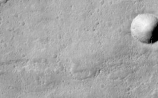 <h1>PIA01431:  Lava Flows On Ascraeus Mons Volcano</h1><div class="PIA01431" lang="en" style="width:800px;text-align:left;margin:auto;background-color:#000;padding:10px;max-height:150px;overflow:auto;"><p><b>Ascraeus Mons Volcano:</b><br> Like Earth, Mars has many volcanoes and volcanic features. This high-resolution view shows some of the lava flows near the summit of Ascraeus Mons, one of the three giant shield volcanoes known as the "Tharsis Montes." Volcanoes form when magma (molten rock) erupts out onto the surface of a planet. Based on Viking-era observations, Ascraeus Mons is considered to be one of the tallest volcanoes on Mars... its summit is more than 11 km (6.8 miles) above the surrounding plain. The summit is more than 23 km (14 miles) higher in elevation than the place where Mars Pathfinder landed in July 1997.<p><b>Description of MOC Image:</b><br> This picture shows an area that is about 20 km (12 miles) higher in elevation than the Mars Pathfinder landing site. The picture shows three main features: (1) a crater at the center-right, (2) a sinuous, discontinuous channel across the upper half, and (3) a rough and pitted, elevated surface across the lower half of the image.<p><b>(1) Crater at center right.</b> Distinguishing meteor craters from volcanic craters can sometimes be a challenge on Mars. This particular crater was most likely formed by meteor impact because it has a raised rim and a faint radial ejecta pattern around the outside of it. This crater is 600 m (2000 feet) across, about 3/4 the size of the famous "Meteor Crater" near Winslow, Arizona.<p><b>(2) Sinuous channel.</b> The type of discontinuous channel running across the upper half of the image is sometimes referred to as a "sinuous rille." These are common on the volcanic plains of the Moon and among volcanoes and volcanic plains on Earth. Such a channel was once a lava tube. It is running down the middle of an old lava flow. The "tube" looks like a "channel" because its roof has collapsed. The discontinuous nature of this channel is the result of the collapse, or "cave-in" of what was once the roof of the lava tube. It is common for certain types of relatively fluid lavas to form lava tubes. As it is being emplaced, the outer margins of the lava flow cool and harden, but the interior remains hot and continues to flow down-hill. Eventually, the eruption stops and the lava inside the tube cools, contracts, and hardens, leaving behind a tube (basically, a long narrow cave).<p><b>(3) Rough elevated surface.</b> The rough, pitted, and elevated surface across the bottom half of the image is a lava flow. The margins of this feature are somewhat lobate in form, and the entire feature is elevated above its surroundings, indicating that it was the last lava flow to pour through this region.<p><b>Putting it All Together: Aa and Pahoehoe Lava Flows:</b><br> Shield volcanoes such as Ascraeus Mons form from relatively fluid lavas. Shield volcanoes on Earth include the well-known Islands of Hawai'i. The kind of lava that is fluid enough to make shield volcanoes is called basalt. This is an iron- and magnesium-rich silicate lava that, when cooled, is usually black or very dark brown.<p>Basalt lava flows come in two main varieties: Aa and Pahoehoe. These are Hawai'ian names. "Aa" (pronounced "ah-ah") lava flows have very rough, jumbly surfaces, and they usually lack lava tubes. "Aa" lava flow surfaces are very rough to walk on-- thus the term "aa" probably refers to the sound a person might make when walking on a cooled/solidified aa flow in bare feet!<p>"Pahoehoe" (pronounced "pa-hoy-hoy") is a term that means "ropey." The surfaces of pahoehoe lava flows are generally very smooth and billowy. Sometimes they have a ropy texture like melted taffy or caramel. Pahoehoe flows very commonly contain lava tubes.<p>The rough-surfaced flow across the lower half of the MOC image is interpreted to be an "aa" lava flow, and the smoother surface with a sinuous channel running down its center is interpreted to be a "pahoehoe" lava flow. Both would indicate that the lavas on Ascraeus Mons, at least at this location, are probably composed of basalt.<p><b>More Picture Information:</b><br> This MOC picture is a subframe of image #26705, centered approximately at 11.5°N latitude, 103.5°W longitude. It was taken on April 28, 1998, at 4:23 AM Universal Time, on Mars Global Surveyor's 267th orbit around Mars. Orbit 267 was the second-to-last orbit on which observations were obtained before Mars and the spacecraft passed behind the Sun for several weeks known as "Solar Conjunction."<p>Malin Space Science Systems and the California Institute of Technology built the MOC using spare hardware from the Mars Observer mission. MSSS operates the camera from its facilities in San Diego, CA. The Jet Propulsion Laboratory's Mars Surveyor Operations Project operates the Mars Global Surveyor spacecraft with its industrial partner, Lockheed Martin Astronautics, from facilities in Pasadena, CA and Denver, CO.http://www.jpl.nasa.gov/galileo/sepo<br /><br /><a href="http://photojournal.jpl.nasa.gov/catalog/PIA01431" onclick="window.open(this.href); return false;" title="Voir l'image 	 PIA01431:  Lava Flows On Ascraeus Mons Volcano	  sur le site de la NASA">Voir l'image 	 PIA01431:  Lava Flows On Ascraeus Mons Volcano	  sur le site de la NASA.</a></div>