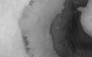 <h1>PIA01433:  Seepage and Ponding within a Southern Hemisphere Crater</h1><div class="PIA01433" lang="en" style="width:800px;text-align:left;margin:auto;background-color:#000;padding:10px;max-height:150px;overflow:auto;">Mars Orbiter Camera (MOC) image 7707 (subframe) reproduced at full resolution, about 24.5 meters/pixel (80.4 feet/pixel). Picture shows an area approximately 25.1 x 31.3 km (15.6 x 19.5 miles) in size. Sun illumination is from the lower left. The MOC image is centered near 65.1°S latitude, 15.1°W longitude. Image was obtained during the Southern Spring season on December 29, 1997, at 1:19 p.m. PST on Mars Global Surveyor's 77th orbit around Mars.<p>Despite evidence of catastrophic floods and integrated valley networks on Mars, unequivocal evidence of ponding has been difficult, if not impossible, to find. MOC image 7707 shows what, at first examination, appears to be such evidence. There are two striking geomorphic attributes of the crater shown in the image: (1) The crater wall shows channeling suggestive of fluid seepage; and (2) The contact (i.e., the boundary between two types of geologic materials) between the dark floor materials and the lighter materials of the crater wall suggests, by the formation of bays and peninsulas, a ponding relationship.<p>These relationships are best and most easily explained if, at some time in the past, water seeped out of layers within the crater wall and flowed down into the crater, flooding part of the crater floor. In this interpretation, the dark material may be sediment transported by the seeping water. The appearance of dunes within the crater may be coincidental, or the sand may have been generated by wind and wave action. The lack of superimposed fresh impact craters suggests this process may have been active relatively recently.<p>It is important to note that both the channel and floor relationships seen in this image may be formed by other processes, and that there is also the possibility that they may not be related (i.e., that the fluid from the channels did not emplace the dark, ponded floor material). It is also important to remember that a fluid other than water, for example, fluid lava, could be responsible for the features seen. Indeed, lower resolution Viking and some MOC images suggest just such an alternative explanation. The absence of craters may reflect the difficulty of the materials to preserve such features, or their burial by dust. Finally, the environmental difficulties of having liquid water seeping from the wall of a south polar crater are quite formidable. For these reasons, caution must be exercised in adopting any specific hypothesis.<p>Malin Space Science Systems and the California Institute of Technology built the MOC using spare hardware from the Mars Observer mission. MSSS operates the camera from its facilities in San Diego, CA. The Jet Propulsion Laboratory's Mars Surveyor Operations Project operates the Mars Global Surveyor spacecraft with its industrial partner, Lockheed Martin Astronautics, from facilities in Pasadena, CA and Denver, CO.<br /><br /><a href="http://photojournal.jpl.nasa.gov/catalog/PIA01433" onclick="window.open(this.href); return false;" title="Voir l'image 	 PIA01433:  Seepage and Ponding within a Southern Hemisphere Crater	  sur le site de la NASA">Voir l'image 	 PIA01433:  Seepage and Ponding within a Southern Hemisphere Crater	  sur le site de la NASA.</a></div>