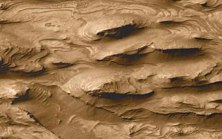 <h1>PIA02839:  Layered Outcrops of Far West Candor Chasma</h1><div class="PIA02839" lang="en" style="width:800px;text-align:left;margin:auto;background-color:#000;padding:10px;max-height:150px;overflow:auto;"><a href="/figures/PIA02839bigfig.jpg"></a><p>Images from Mariner 9 in 1972 revealed that some of the mesas and mounds found within the chasms of the martian "Grand Canyon"--the Valles Marineris--have layers in them. Speculations as to the origin of these interior layered materials ranged from volcanic ash deposits to sediments laid down in lakes that could have partially filled the Vallis Marineris troughs, much as lakes now occupy portions of the rift valleys of eastern Africa. The proposal that the Valles Marineris once hosted deep martian lakes led to additional speculation as to the prospects for finding fossil evidence of martian life.<p>Mars Global Surveyor (MGS) Mars Orbiter Camera (MOC) images have ten or more times better resolution than the Mariner 9 and Viking orbiter images taken in the 1970s. MOC images have indeed confirmed the presence of layered outcrops within the Valles Marineris. They have also shown places previously not suspected to have layered rock, and they have shown that these materials might not have formed in the Valles Marineris, but were instead deposited in craters that were subsequently buried long before the chasms opened up (see discussion below). The layered rock is now visible because of faulting and erosion.<p>The high resolution picture shown here (B, above right) was the first image received by MOC scientists that began to hint at a larger story of layered sedimentary rock on Mars. The picture shows a 1.5 km by 2.9 km (0.9 mi by 1.8 mi) area in far southwestern Candor Chasma (A, above left) that was--based on Mariner 9 and Viking orbiter images--not previously expected to exhibit layers. The MOC image reveals that the floor of western Candor Chasma at this location is indeed layered. What is most striking about the picture is the large number and uniformity of the layers, or beds. There are over 100 beds in this area, and each has about the same thickness (estimated to be about 10 meters (11 yards) thick). Each layer has a relatively smooth upper surface, and each is hard enough to form steep cliffs at its margins.<p>Layers indicate change. The uniform pattern seen here--beds of similar properties and thickness repeated over a hundred times--suggest that the deposition of materials that made the layers was interrupted at regular or episodic intervals. Patterns like this, when found on Earth, usually indicate the presence of sediment deposited in dynamic, energetic, underwater environments. On Mars, these same patterns could very well indicate that the materials were deposited in a lake or shallow sea. Other MOC images suggest that these layers would not have formed in a lake in Candor Chasma, but instead were deposited in a crater or other basin that existed before Candor Chasma was cut (by faulting and erosion) into the surrounding terrain. However, it is not known for certain that these materials actually formed underwater, for it is possible that there were uniquely Martian processes occurring in the distant past that would mimic the pattern of sedimentation in water. For example, if the early Martian atmosphere was denser than it is today, and if the planet's atmospheric pressure changed on a cyclic basis (as it does today), then perhaps these materials are simply deposits of airborne dust that were later buried and cemented to create cliff-forming rock.<p>Sunlight illuminates both the wide angle context view and the narrow angle high resolution image from the left/upper left. In both, north is toward the top and east to the right.<br /><br /><a href="http://photojournal.jpl.nasa.gov/catalog/PIA02839" onclick="window.open(this.href); return false;" title="Voir l'image 	 PIA02839:  Layered Outcrops of Far West Candor Chasma	  sur le site de la NASA">Voir l'image 	 PIA02839:  Layered Outcrops of Far West Candor Chasma	  sur le site de la NASA.</a></div>