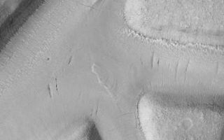 <h1>PIA03752:  Mesas and troughs in Nilosyrtis region, Mars</h1><div class="PIA03752" lang="en" style="width:372px;text-align:left;margin:auto;background-color:#000;padding:10px;max-height:150px;overflow:auto;">This Mars Global Surveyor (MGS) Mars Orbiter Camera (MOC) image shows a region of flat-topped mesas separated by valleys or troughs of similar depth and width. The valley floors have been covered by a material that has subsequently developed thin cracks and collapse pits aligned along some of these cracks. A few outcrops of layered material occur in the valleys as well. The valleys probably originally formed by faulting; the origin of the mantling material is unknown. The image covers an area approximately 2.3 km (1.4 miles) wide and was acquired in May 2001. Sunlight illuminates the scene from the lower left.<br /><br /><a href="http://photojournal.jpl.nasa.gov/catalog/PIA03752" onclick="window.open(this.href); return false;" title="Voir l'image 	 PIA03752:  Mesas and troughs in Nilosyrtis region, Mars	  sur le site de la NASA">Voir l'image 	 PIA03752:  Mesas and troughs in Nilosyrtis region, Mars	  sur le site de la NASA.</a></div>
