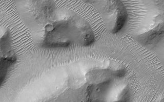 <h1>PIA03779:  Nirgal Vallis and its Windblown Dunes</h1><div class="PIA03779" lang="en" style="width:696px;text-align:left;margin:auto;background-color:#000;padding:10px;max-height:150px;overflow:auto;">Nirgal Vallis is a narrow valley system that stretches approximately 420 kilometers (260 miles) across the martian surface near 28°S latitude, north of the large basin, Argyre. The floor of the valley system is largely covered with light-toned dunes and ripples. These windblown features obscure most of the original morphology of the valley floor. This view of a small portion of Nirgal Vallis was obtained by the Mars Global Surveyor (MGS) Mars Orbiter Camera (MOC) during Extended Mission subphase E02 on March 29, 2001. In each short tributary valley, dunes have a somewhat different orientation compared to those in the other valleys. The dune patterns here indicate that winds are locally controlled by the shape and orientation of each valley. The dunes just left of the center of the image have small craters on them, formed by meteor impact. The craters indicate that the dunes are not fresh, modern features, but are considerably older than they might at first seem. This image covers an area 3 km (1.9 mi) wide and is illuminated from the upper left.<br /><br /><a href="http://photojournal.jpl.nasa.gov/catalog/PIA03779" onclick="window.open(this.href); return false;" title="Voir l'image 	 PIA03779:  Nirgal Vallis and its Windblown Dunes	  sur le site de la NASA">Voir l'image 	 PIA03779:  Nirgal Vallis and its Windblown Dunes	  sur le site de la NASA.</a></div>