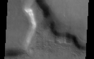 <h1>PIA03787:  Clouds in the Northern Tempe Terra</h1><div class="PIA03787" lang="en" style="width:465px;text-align:left;margin:auto;background-color:#000;padding:10px;max-height:150px;overflow:auto;"><br>(Released 2 May 2002)<br><b>The Science</b><br>This THEMIS visible image shows a region in northern Tempe Terra near 48° N, 75° W (285° E). Patchy water-ice clouds cover portions of the low-lying canyon at the top (north) of this image. Further south the atmosphere is clear and the knobby or "scabby" plains that are typical of many mid-latitude regions on Mars can be seen. These plains appear to mantle and modify a pre-existing surface, burying the older cratered terrain. This mantling layer has itself been modified to produce a pitted, knobby surface. The large mesa seen in this image has unusual deposits of material that occur preferentially on the cold, north-facing slopes. These deposits are seen frequently at mid-northern and southern latitudes, and have a distinct, rounded boundary that typically occurs at approximately the same distance below the ridge crest. It has been suggested that these deposits once draped the entire surface and have since been removed from all but the north-facing slopes. The presence of water ice in these layers is a likely possibility to account for their preservation only on the colder surfaces. The south-facing slopes lack this mantling material, and show clear evidence for layering in the rock units that form the mesa.<br><br><b>The Story</b><br>This deep and murky-looking depression is in an area called "Tempe Terra," a lilting, alliterative name that seems almost a little too merry for this kind of terrain.<br><br>If the top of the image looks a little smudgy, that's because patchy water-ice clouds hang over the low lying canyon. Further south, where the air is clear, you can see some "scabby" plains (particularly in the high-res image, where the knobby patches of raised surface areas sort of do look like crusted-over dirt wounds). These plains cover a more ancient, cratered surface, but have been eroded away enough to form these scabby-seeming features.<br><br>The large mesa in this image has some odd deposits of material on its cold, north-facing slopes. Could these deposits have been all over the surface of Mars long ago, but then were subsequently eroded away in most places on the planet? Did water ice on the colder surfaces preserve the last vestiges of these deposits so that scientists have the advantage of studying them today?<br><br>While those answers won't be clear for a while, the south-facing slopes don't have this piled on material. That makes it easier to see the rock layers in the mesa. Layers are important to study, because they tell what has happened to the planet geologically over its history. The bottom layers are usually the oldest (unless some geologic force has pushed them up), so looking at each layer can give an idea of what happened first and last . . . and maybe even how long each period of time lasted.<br /><br /><a href="http://photojournal.jpl.nasa.gov/catalog/PIA03787" onclick="window.open(this.href); return false;" title="Voir l'image 	 PIA03787:  Clouds in the Northern Tempe Terra	  sur le site de la NASA">Voir l'image 	 PIA03787:  Clouds in the Northern Tempe Terra	  sur le site de la NASA.</a></div>