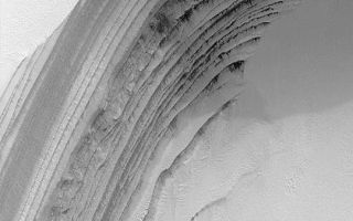 <h1>PIA04500:  Frosty North Polar Layers</h1><div class="PIA04500" lang="en" style="width:540px;text-align:left;margin:auto;background-color:#000;padding:10px;max-height:150px;overflow:auto;">MGS MOC Release No. MOC2-349, 3 May 2003<p>This Mars Global Surveyor (MGS) Mars Orbiter Camera (MOC) image is a springtime view of frost-covered layers revealed by an eroded scarp in the martian north polar cap. The layers are thought to consist of a mixture of dust, ice, and possibly sand. Some layers are known to be a source for dark sand that occurs in nearby dunes. During the summer, this surface would be considerably darker because most of the bright frost sublimes away during the spring season. The picture covers an area about 3 km (1.9 mi) wide near 85.2°N, 4.4°W. Sunlight illuminates the scene from the lower left.<p><br /><br /><a href="http://photojournal.jpl.nasa.gov/catalog/PIA04500" onclick="window.open(this.href); return false;" title="Voir l'image 	 PIA04500:  Frosty North Polar Layers	  sur le site de la NASA">Voir l'image 	 PIA04500:  Frosty North Polar Layers	  sur le site de la NASA.</a></div>