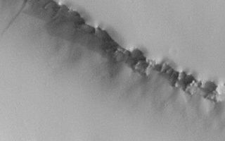 <h1>PIA04515:  Dust Mantle Near Pavonis Mons</h1><div class="PIA04515" lang="en" style="width:540px;text-align:left;margin:auto;background-color:#000;padding:10px;max-height:150px;overflow:auto;">MGS MOC Release No. MOC2-356, 10 May 2003<p>This Mars Global Surveyor (MGS) Mars Orbiter Camera (MOC) image shows a thick mantle of dust covering lava flows north of Pavonis Mons so well that the flows are no longer visible. Flows are known to occur here because of the proximity to the volcano, and such flows normally have a very rugged surface. Fine dust, however, has settled out of the atmosphere over time and obscured the flows from view. The cliff at the top of the image faces north (up), the cliff in the middle of the image faces south (down), and the rugged slope at the bottom of the image faces north (up). The dark streak at the center-left was probably caused by an avalanche of dust sometime in the past few decades. The image is located near 4.1°N, 111.3°W. Sunlight illuminates the scene from the right/lower right.<p><br /><br /><a href="http://photojournal.jpl.nasa.gov/catalog/PIA04515" onclick="window.open(this.href); return false;" title="Voir l'image 	 PIA04515:  Dust Mantle Near Pavonis Mons	  sur le site de la NASA">Voir l'image 	 PIA04515:  Dust Mantle Near Pavonis Mons	  sur le site de la NASA.</a></div>