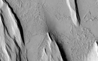 <h1>PIA04518:  Yardangs and Exhumation</h1><div class="PIA04518" lang="en" style="width:540px;text-align:left;margin:auto;background-color:#000;padding:10px;max-height:150px;overflow:auto;">MGS MOC Release No. MOC2-359, 13 May 2003<p>This Mars Global Surveyor (MGS) Mars Orbiter Camera (MOC) image shows the results of wind erosion of a thick deposit of fine-grained, cemented material. The ridges oriented roughly from upper left to lower right (northwest to southeast) are called yardangs. Similar features occur in some of Earth's desert regions. The flat surface with narrow, sinuous ridges at the top (north) end of the picture is interpreted to be an ancient lava plain that is being slowly revealed as the overlying materials are eroded away. This picture is located near 13.2°N, 159.9°W. Sunlight illuminates the scene from the left/lower left.<p><br /><br /><a href="http://photojournal.jpl.nasa.gov/catalog/PIA04518" onclick="window.open(this.href); return false;" title="Voir l'image 	 PIA04518:  Yardangs and Exhumation	  sur le site de la NASA">Voir l'image 	 PIA04518:  Yardangs and Exhumation	  sur le site de la NASA.</a></div>