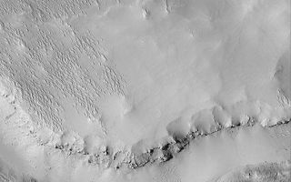 <h1>PIA04565:  Terrain Near Gordii Dorsum</h1><div class="PIA04565" lang="en" style="width:540px;text-align:left;margin:auto;background-color:#000;padding:10px;max-height:150px;overflow:auto;">MGS MOC Release No. MOC2-383, 6 June 2003<p>Small ridges known as yardangs in the upper left quarter of this April 2003 Mars Global Surveyor (MGS) Mars Orbiter Camera (MOC) image indicate that wind has stripped away a mantling layer of sediment to reveal the terrain beneath. Layers and boulders on the cliff face near the south-center of the image show that the substrate is quite competent; its location southwest of Olympus Mons near Gordii Dorsum suggests the bedrock here may include old lava flows. The picture is located near 4.8°N, 142.7°W. Sunlight illuminates the scene from the left/lower left.<p><br /><br /><a href="http://photojournal.jpl.nasa.gov/catalog/PIA04565" onclick="window.open(this.href); return false;" title="Voir l'image 	 PIA04565:  Terrain Near Gordii Dorsum	  sur le site de la NASA">Voir l'image 	 PIA04565:  Terrain Near Gordii Dorsum	  sur le site de la NASA.</a></div>
