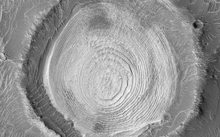 <h1>PIA04592:  Schiaparelli Sedimentary Rocks</h1><div class="PIA04592" lang="en" style="width:540px;text-align:left;margin:auto;background-color:#000;padding:10px;max-height:150px;overflow:auto;">MGS MOC Release No. MOC2-403, 26 June 2003<p>Some of the most important high resolution imaging results of the Mars Global Surveyor (MGS) Mars Orbiter Camera (MOC) experiment center on discoveries about the presence and nature of the sedimentary rock record on Mars. This old meteor impact crater in northwestern Schiaparelli Basin exhibits a spectacular view of layered, sedimentary rock. The 2.3 kilometer (1.4 miles) wide crater may have once been completely filled with sediment; the material was later eroded to its present form. Dozens of layers of similar thickness and physical properties are now expressed in a wedding cake-like stack in the middle of the crater. Sunlight illuminating the scene from the left shows that the circle, or mesa top, at the middle of the crater stands higher than the other stair-stepped layers. The uniform physical properties and bedding of these layers might indicate that they were originally deposited in a lake (it is possible that the crater was at the bottom of a much larger lake, filling Schiaparelli Basin); alternatively, the layers were deposited by settling out of the atmosphere in a dry environment. This picture was acquired on June 3, 2003, and is located near 0.9°S, 346.2°W.<p><br /><br /><a href="http://photojournal.jpl.nasa.gov/catalog/PIA04592" onclick="window.open(this.href); return false;" title="Voir l'image 	 PIA04592:  Schiaparelli Sedimentary Rocks	  sur le site de la NASA">Voir l'image 	 PIA04592:  Schiaparelli Sedimentary Rocks	  sur le site de la NASA.</a></div>