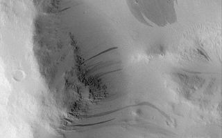 <h1>PIA04613:  Dark Slope Streaks</h1><div class="PIA04613" lang="en" style="width:540px;text-align:left;margin:auto;background-color:#000;padding:10px;max-height:150px;overflow:auto;">MGS MOC Release No. MOC2-412, 5 July 2003<p>On the dry, desert planet, Mars, wind is not the only contemporary geologic process that modifies the surface. Gravity also has a role to play. In regions such as Amazonis, Tharsis, and Arabia, most surfaces are covered by mantles of very fine dust. From time to time, an avalanche occurs on a dust-covered slope. This process is happening today, because changes have been observed by the Mars Global Surveyor (MGS) Mars Orbiter Camera (MOC) over the course if its mission, which began in September 1997. This picture shows a variety of dark slope streaks, formed by avalanches of dust, on the walls of a crater in southwest Amazonis near 7.6°N, 171.8°W. The size and shape of each slope streak, including the wide feature near the upper right, is determined by the steepness and texture of the slope on which it occurs. New slope streaks in some regions have been observed to form over periods of less than a few months to a year. This picture was taken in June 2003, and is illuminated from the lower left. The image is 2.3 km (1.4 mi) wide.<p><br /><br /><a href="http://photojournal.jpl.nasa.gov/catalog/PIA04613" onclick="window.open(this.href); return false;" title="Voir l'image 	 PIA04613:  Dark Slope Streaks	  sur le site de la NASA">Voir l'image 	 PIA04613:  Dark Slope Streaks	  sur le site de la NASA.</a></div>