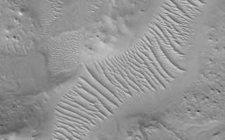 <h1>PIA04757:  Ancient Valley</h1><div class="PIA04757" lang="en" style="width:672px;text-align:left;margin:auto;background-color:#000;padding:10px;max-height:150px;overflow:auto;">MGS MOC Release No. MOC2-491, 22 September 2003<p />Auqakuh Vallis is an ancient valley system that might have once been a conduit for liquid water flowing north, across northeastern Arabia Terra, toward the Nilosyrtis region. This Mars Global Surveyor (MGS) Mars Orbiter Camera (MOC) image shows a portion of the Auqakuh Vallis system. The valley was cut into layered bedrock. It was once much deeper than today, but much of the surrounding materials have been eroded away. Windblown sediments now cover the floor of the valley, a reflection of the parched conditions of the modern martian environment. This picture is located near 29.1°N, 299.6°W, and covers an area 3 km (1.9 mi) across. Sunlight illuminates the scene from the lower left.<br /><br /><a href="http://photojournal.jpl.nasa.gov/catalog/PIA04757" onclick="window.open(this.href); return false;" title="Voir l'image 	 PIA04757:  Ancient Valley	  sur le site de la NASA">Voir l'image 	 PIA04757:  Ancient Valley	  sur le site de la NASA.</a></div>