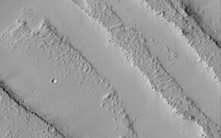 <h1>PIA04761:  Dusty Troughs</h1><div class="PIA04761" lang="en" style="width:674px;text-align:left;margin:auto;background-color:#000;padding:10px;max-height:150px;overflow:auto;">MGS MOC Release No. MOC2-494, 25 September 2003<p />This Mars Global Surveyor (MGS) Mars Orbiter Camera (MOC) picture shows dust-mantled troughs formed by faulting on the plains northeast of the volcano, Ascraeus Mons. The smooth areas are covered with thick accumulations of dust, the rougher surfaces are lava flows that also have been blanketed by dust. Thick accumulations of dust are common throughout the Tharsis volcanic region of Mars. This picture is located near 8.3°N, 117.5°W, and covers an area 3 km (1.9 mi) across. Sunlight illuminates the scene from the lower left.<br /><br /><a href="http://photojournal.jpl.nasa.gov/catalog/PIA04761" onclick="window.open(this.href); return false;" title="Voir l'image 	 PIA04761:  Dusty Troughs	  sur le site de la NASA">Voir l'image 	 PIA04761:  Dusty Troughs	  sur le site de la NASA.</a></div>
