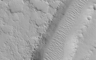 <h1>PIA04782:  Valley Near Nilus Chaos</h1><div class="PIA04782" lang="en" style="width:673px;text-align:left;margin:auto;background-color:#000;padding:10px;max-height:150px;overflow:auto;">MGS MOC Release No. MOC2-504, 5 October 2003<p />This August 2003 Mars Global Surveyor (MGS) Mars Orbiter Camera (MOC) image shows a valley near Nilus Chaos, around 25.2°N, 80.3°W. The scene has a uniform albedo, indicating that all of the landforms are probably mantled by fine, bright dust. Dark streaks on the valley walls indicate places where recent dust avalanches have occurred. The ripple-like dune features on the valley floor were formed by wind, but today they are inactive and covered with dust. A few craters, created by impacting debris, have formed on the dunes, again attesting to their inactivity in the modern martian environment. The image covers an area 3 km (1.9 mi) wide; it is illuminated by sunlight from the lower left.<br /><br /><a href="http://photojournal.jpl.nasa.gov/catalog/PIA04782" onclick="window.open(this.href); return false;" title="Voir l'image 	 PIA04782:  Valley Near Nilus Chaos	  sur le site de la NASA">Voir l'image 	 PIA04782:  Valley Near Nilus Chaos	  sur le site de la NASA.</a></div>