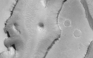 <h1>PIA05210:  Granicus Valles</h1><div class="PIA05210" lang="en" style="width:640px;text-align:left;margin:auto;background-color:#000;padding:10px;max-height:150px;overflow:auto;">15 January 2004 <br /> This Mars Global Surveyor (MGS) Mars Orbiter Camera (MOC) image shows some of the troughs of the Granicus Valles system, located west of the Elysium volcanic rise near 27.1°N, 224.0°W. The floors exhibit abundant large ripple-like features deposited and shaped by wind. The dark dots on the valley floors are large boulders. The image covers an area approximately 3 km (1.9 mi) wide; sunlight illuminates the scene from the left.<br /><br /><a href="http://photojournal.jpl.nasa.gov/catalog/PIA05210" onclick="window.open(this.href); return false;" title="Voir l'image 	 PIA05210:  Granicus Valles	  sur le site de la NASA">Voir l'image 	 PIA05210:  Granicus Valles	  sur le site de la NASA.</a></div>