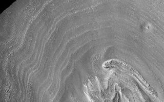 <h1>PIA05294:  Crater Floor Bands</h1><div class="PIA05294" lang="en" style="width:601px;text-align:left;margin:auto;background-color:#000;padding:10px;max-height:150px;overflow:auto;">12 February 2004 <br /> The somewhat concentric bands in this Mars Global Surveyor (MGS) Mars Orbiter Camera (MOC) image may be an expression of eroded layered material. The crater in which these occur is found at middle southern latitude near the west rim of the giant Hellas impact basin. The picture is located near 36.6°S, 321.2°W. Sunlight illuminates the scene from the upper left; the image covers an area 3 km (1.9 mi) wide.<br /><br /><a href="http://photojournal.jpl.nasa.gov/catalog/PIA05294" onclick="window.open(this.href); return false;" title="Voir l'image 	 PIA05294:  Crater Floor Bands	  sur le site de la NASA">Voir l'image 	 PIA05294:  Crater Floor Bands	  sur le site de la NASA.</a></div>