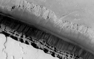 <h1>PIA05698:  Cerberus Fossae Trough</h1><div class="PIA05698" lang="en" style="width:672px;text-align:left;margin:auto;background-color:#000;padding:10px;max-height:150px;overflow:auto;">24 March 2004<br />This Mars Global Surveyor (MGS) Mars Orbiter Camera (MOC) image provides a look down into one of the long, dark, Cerberus Fossae troughs near 10.2°N, 202.6°W. Faulting and extension of the upper martian crust in this region has caused numerous troughs such as this to form. The trough walls expose layered bedrock that serves as a source for dark-toned debris that creates talus deposits. This picture covers an area about 3 km (1.9 mi) across. Sunlight illuminates the scene from the lower left.<br /><br /><a href="http://photojournal.jpl.nasa.gov/catalog/PIA05698" onclick="window.open(this.href); return false;" title="Voir l'image 	 PIA05698:  Cerberus Fossae Trough	  sur le site de la NASA">Voir l'image 	 PIA05698:  Cerberus Fossae Trough	  sur le site de la NASA.</a></div>