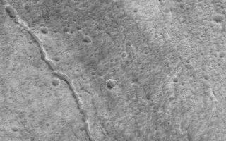 <h1>PIA05710:  Lava Tubes of Olympus</h1><div class="PIA05710" lang="en" style="width:512px;text-align:left;margin:auto;background-color:#000;padding:10px;max-height:150px;overflow:auto;">5 April 2004<br />This Mars Global Surveyor (MGS) Mars Orbiter Camera (MOC) image shows evidence of two collapsed lava tubes on the southeast flank of the giant martian volcano, Olympus Mons. One runs diagonally across the entire image, the other is shorter and does not extend across the whole image. The shorter one is a series of pits and troughs, rather than a continuous channel. Lava flowed in tubes under the surface; later, the roof of each tube collapsed to form a series of pits and troughs which, in the larger example, eventually coalesced to its present, channel-like form. The image is located near 16.8°N, 132.2°W, and covers an area about 3 km (1.9 mi) across. Sunlight illuminates the scene from the lower left.<br /><br /><a href="http://photojournal.jpl.nasa.gov/catalog/PIA05710" onclick="window.open(this.href); return false;" title="Voir l'image 	 PIA05710:  Lava Tubes of Olympus	  sur le site de la NASA">Voir l'image 	 PIA05710:  Lava Tubes of Olympus	  sur le site de la NASA.</a></div>