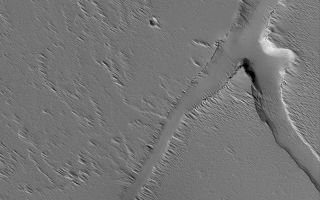<h1>PIA06695:  Troughs Near Ascraeus</h1><div class="PIA06695" lang="en" style="width:800px;text-align:left;margin:auto;background-color:#000;padding:10px;max-height:150px;overflow:auto;"><p>18 July 2004<br />This Mars Global Surveyor (MGS) Mars Orbiter Camera (MOC) image shows troughs and a pit, possibly formed by collapse, on the volcanic plains south of the large volcano, Ascraeus Mons. Wind-eroded debris mantles the scene and partly fills the depressions. The image is located near 4.5°N, 105.5°W, and covers an area about 3 km (1.9 mi) wide. Sunlight illuminates the scene from the lower left.</p><br /><br /><a href="http://photojournal.jpl.nasa.gov/catalog/PIA06695" onclick="window.open(this.href); return false;" title="Voir l'image 	 PIA06695:  Troughs Near Ascraeus	  sur le site de la NASA">Voir l'image 	 PIA06695:  Troughs Near Ascraeus	  sur le site de la NASA.</a></div>