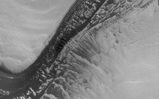 <h1>PIA06799:  Frosty Polar Slope</h1><div class="PIA06799" lang="en" style="width:672px;text-align:left;margin:auto;background-color:#000;padding:10px;max-height:150px;overflow:auto;"><p>11 August 2004<br />Acquired just last week on 3 August 2004, this Mars Global Surveyor (MGS) Mars Orbiter Camera (MOC) image shows a dark, layered scarp in the martian north polar region. All of the light-toned surfaces in this image are covered by frost left over from the previous winter. On the scarp, about half of the surfaces once covered by frost are now exposed (as the frost has sublimed away), leaving a large number of bright patches. These patches of frost enhance the appearance of layering on the slopes. This image is located near 81.8°N, 84.4°W. The image covers an area 3 km (1.9 mi) wide, and is illuminated by sunlight from the lower left.</p><br /><br /><a href="http://photojournal.jpl.nasa.gov/catalog/PIA06799" onclick="window.open(this.href); return false;" title="Voir l'image 	 PIA06799:  Frosty Polar Slope	  sur le site de la NASA">Voir l'image 	 PIA06799:  Frosty Polar Slope	  sur le site de la NASA.</a></div>
