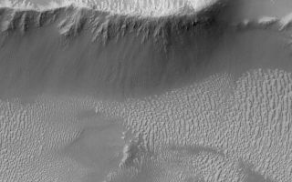 <h1>PIA06943:  Valles Marineris Features</h1><div class="PIA06943" lang="en" style="width:800px;text-align:left;margin:auto;background-color:#000;padding:10px;max-height:150px;overflow:auto;"><p>17 October 2004<br >This Mars Global Surveyor (MGS) Mars Orbiter Camera (MOC) image shows light-toned, ripple-like, windblown bedforms and ridges with dark talus accumulations on their slopes in the western portion of the vast Valles Marineris trough system. These features are located near Oudemans Crater around 7.6°S, 91.2°W. The image covers an area about 3 km (1.9 mi) wide and sunlight illuminates the scene from the upper left.</p><br /><br /><a href="http://photojournal.jpl.nasa.gov/catalog/PIA06943" onclick="window.open(this.href); return false;" title="Voir l'image 	 PIA06943:  Valles Marineris Features	  sur le site de la NASA">Voir l'image 	 PIA06943:  Valles Marineris Features	  sur le site de la NASA.</a></div>