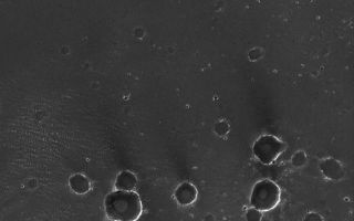 <h1>PIA07151:  Meridiani Craters</h1><div class="PIA07151" lang="en" style="width:608px;text-align:left;margin:auto;background-color:#000;padding:10px;max-height:150px;overflow:auto;"><p>26 December 2004<br >A little over 11 months ago, the Mars Exploration Rover, Opportunity, landed on Meridiani Planum. This Mars Global Surveyor (MGS) Mars Orbiter Camera (MOC) image shows a small portion of Meridiani Planum -- too far from the rover for it to investigate--that has been peppered with small impact craters. The majority of craters, particularly those in the lower half of the image, are secondary impacts caused by the landing of rock and debris ejected from a much larger impact crater, located elsewhere in the region. The large, nearly circular depression at the top center of the image is the site of a much older crater that was filled and almost completely buried beneath the plains. As result of the rover's work in Meridiani Planum, it is now known that the bright rims and walls of the craters are, at least in part, exposures of sedimentary rock. The dark material covering the plains, according to rover results, is mostly very fine sand plus millimeter-sized granules. This picture covers an area about 3 km (1.9 mi) across, and is located near 2.5°S, 3.3°W. Sunlight illuminates the scene from the left.</p><br /><br /><a href="http://photojournal.jpl.nasa.gov/catalog/PIA07151" onclick="window.open(this.href); return false;" title="Voir l'image 	 PIA07151:  Meridiani Craters	  sur le site de la NASA">Voir l'image 	 PIA07151:  Meridiani Craters	  sur le site de la NASA.</a></div>