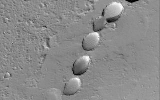 <h1>PIA08494:  Pitted Plain</h1><div class="PIA08494" lang="en" style="width:800px;text-align:left;margin:auto;background-color:#000;padding:10px;max-height:150px;overflow:auto;"><p>28 May 2006<br />This Mars Global Surveyor (MGS) Mars Orbiter Camera (MOC) image shows a chain of collapse pits on a dust-mantled, lava-covered plain northeast of Ascraeus Mons -- one of the giant volcanoes located in the Tharsis region of Mars. Pit chains are associated with collapse which may be driven by several processes including, but not limited to, crustal extension owing to tectonic processes and the collapse of the roof of a lava tube.</p><p>Location near: 14.8°N, 99.1°W <br />Image width: ~3 km (~1.9 mi) <br />Illumination from: lower left <br />Season: Northern Winter </p><br /><br /><a href="http://photojournal.jpl.nasa.gov/catalog/PIA08494" onclick="window.open(this.href); return false;" title="Voir l'image 	 PIA08494:  Pitted Plain	  sur le site de la NASA">Voir l'image 	 PIA08494:  Pitted Plain	  sur le site de la NASA.</a></div>