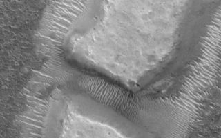 <h1>PIA08512:  Diced Remnant</h1><div class="PIA08512" lang="en" style="width:572px;text-align:left;margin:auto;background-color:#000;padding:10px;max-height:150px;overflow:auto;"><p>5 June 2006<br />This Mars Global Surveyor (MGS) Mars Orbiter Camera (MOC) image shows blocky remnants of a material that was once more laterally extensive on the floor of an impact crater located northwest of Herschel Crater on Mars. Large ripples of windblown sediment have accumulated around and between the blocks.</p><p>Location near: 8.6°S, 236.3°W <br />Image width: ~3 km (~1.9 mi) <br />Illumination from: upper left <br />Season: Southern Summer </p><br /><br /><a href="http://photojournal.jpl.nasa.gov/catalog/PIA08512" onclick="window.open(this.href); return false;" title="Voir l'image 	 PIA08512:  Diced Remnant	  sur le site de la NASA">Voir l'image 	 PIA08512:  Diced Remnant	  sur le site de la NASA.</a></div>