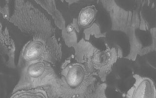 <h1>PIA04902:  Layer Outcrops and Dunes</h1><div class="PIA04902" lang="en" style="width:800px;text-align:left;margin:auto;background-color:#000;padding:10px;max-height:150px;overflow:auto;">MGS MOC Release No. MOC2-561, 1 December 2003<p />This October 2003 Mars Global Surveyor (MGS) Mars Orbiter Camera (MOC) picture shows dark, windblown sand dunes amid outcrops of light-toned, sedimentary rock in a crater in western Arabia Terra. The darkest material in the scene is windblown sand; the steep slopes--the slip faces--of the dunes face toward the southwest (lower left), indicating that wind transport of sand has been from the northeast (upper right). The layered mounds are the remains of sedimentary rock that were once more extensive across this crater floor. The image is located near 8.9°N, 1.2°W, and covers an area 3 km (1.9 mi) wide. Sunlight illuminates the scene from the lower left.<br /><br /><a href="http://photojournal.jpl.nasa.gov/catalog/PIA04902" onclick="window.open(this.href); return false;" title="Voir l'image 	 PIA04902:  Layer Outcrops and Dunes	  sur le site de la NASA">Voir l'image 	 PIA04902:  Layer Outcrops and Dunes	  sur le site de la NASA.</a></div>