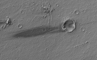 <h1>PIA05807:  Daedalia Streak</h1><div class="PIA05807" lang="en" style="width:800px;text-align:left;margin:auto;background-color:#000;padding:10px;max-height:150px;overflow:auto;"><p>26 April 2004<br />This April 2004 Mars Global Surveyor (MGS) Mars Orbiter Camera (MOC) image shows a dark wind streak on the lee (downwind) side of a small meteor impact crater in western Daedalia Planum. The substrate in this region consists of large lava flows (larger than the image shown here). The winds responsible for the streak came from the east/northeast (right). This picture is located near 15.4°S, 138.1°W, and covers an area about 3 km (1.9 mi) across. Sunlight illuminates the scene from the upper left.</p><br /><br /><a href="http://photojournal.jpl.nasa.gov/catalog/PIA05807" onclick="window.open(this.href); return false;" title="Voir l'image 	 PIA05807:  Daedalia Streak	  sur le site de la NASA">Voir l'image 	 PIA05807:  Daedalia Streak	  sur le site de la NASA.</a></div>